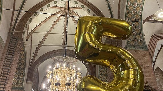 Eine aufblasbare Fünf aus goldener Folie im Schleswiger Dom