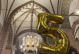 Eine aufblasbare Fünf aus goldener Folie im Schleswiger Dom