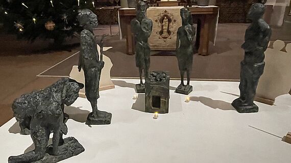 verschiedene Krippenfiguren aus Bronze sind auf einer weißen Fläche aufgestellt. 