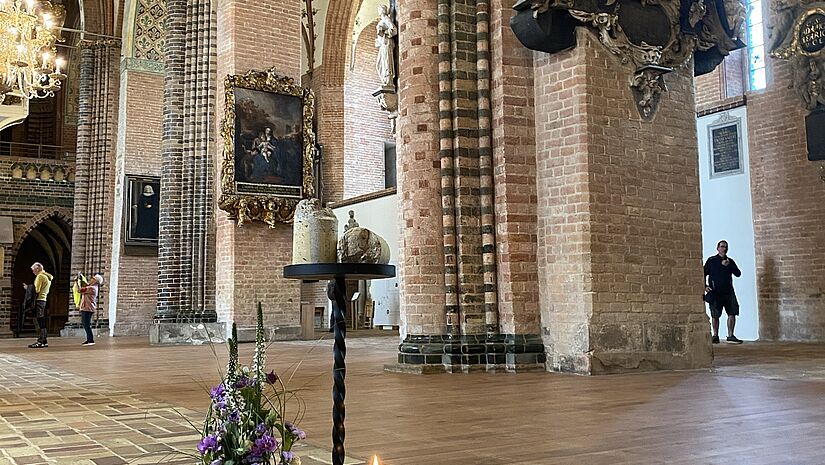 Blick auf den Boden des leeren Schleswiger Doms mit arrangierten Blumen und Kerzen.