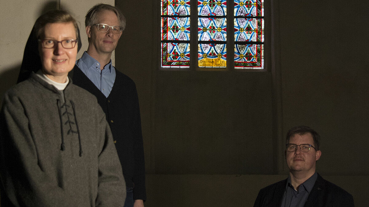 Schwester Maria Magdalena, Kiel, Pastor Mathias Benckert, Oberkirchenrat, Kiel, und Pastor Jörg Jackisch, Fundraising-Beauftragter in der Bischofskanzlei Schleswig, vor dem Kreuzigungsfenster im Schleswiger Dom