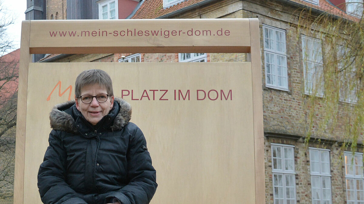 Pröpstin Johanna Lenz-Aude nimmt Platz auf einem Riesenstuhl, der den neuen Domstühlen nachempfunden ist.