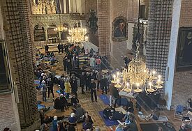 Der Blick von oben auf das Innere des Schleswiger Doms mit vielen Menschen, die durcheinander liegen, gehen, stehen oder sitzen