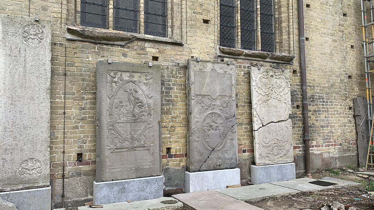 Mehrere der zahlreichen Grabplatten mit den Resten von Ornamenten und Schriftzügen sind im Hof des Kreuzganges im Schleswiger Dom aufgestellt. 