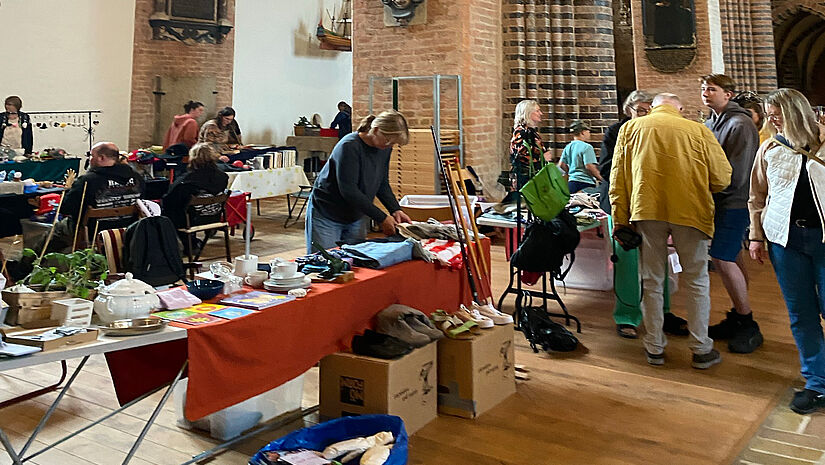 Ein voller Flohmarktstand und Menschen im Schleswiger Dom