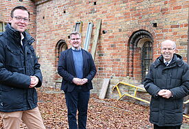 Heiko Ewert (1. Vorsitzender des St. Petri-Domvereins), Pastor Jörg Jackisch (Fundraising-Referent), Bischof Gothart Magaard auf der Nordseite des Domes. Im Giebel oberhalb befindet sich zwei der „Romanischen“ Fenster. Foto: Wendt/Nordkirche