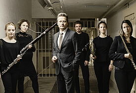 Der Schauspieler Roman Knizka im Kreis von Musikerinnen und Musikern von Opus 45