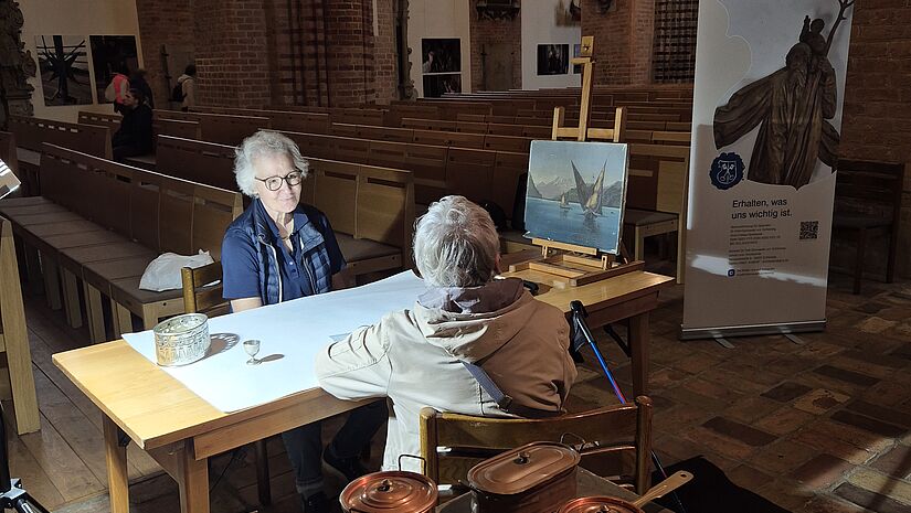 Zwei Frauen am Tisch in einer Kirche im Gespräch