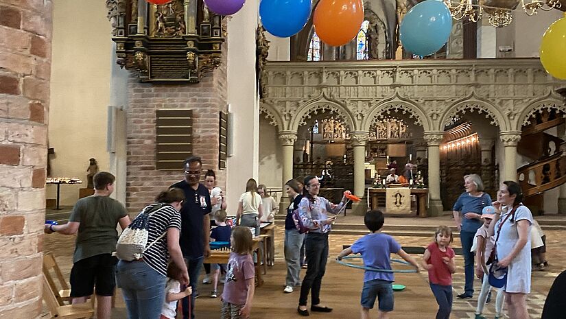 Kinder spielen in einer Kirche, die mit Luftballons geschmückt ist.